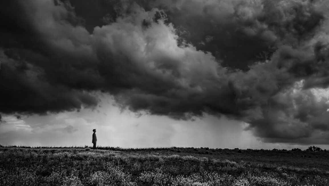 Person standing below ominous clouds